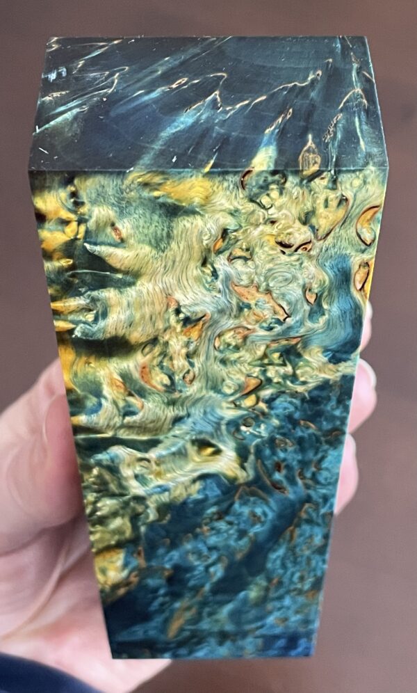 A block of curly birch, also known as masur birch, showcasing its distinctive curly-grained pattern in rich blue and golden tones.